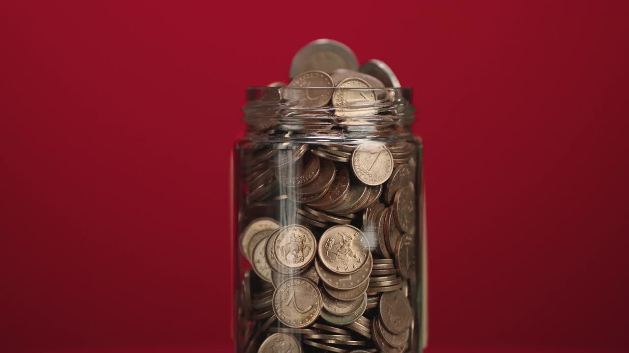 旋转玻璃罐装满硬币和两欧元硬币与粘贴的粘性纸条与加密投资文本在红色背景视频素材