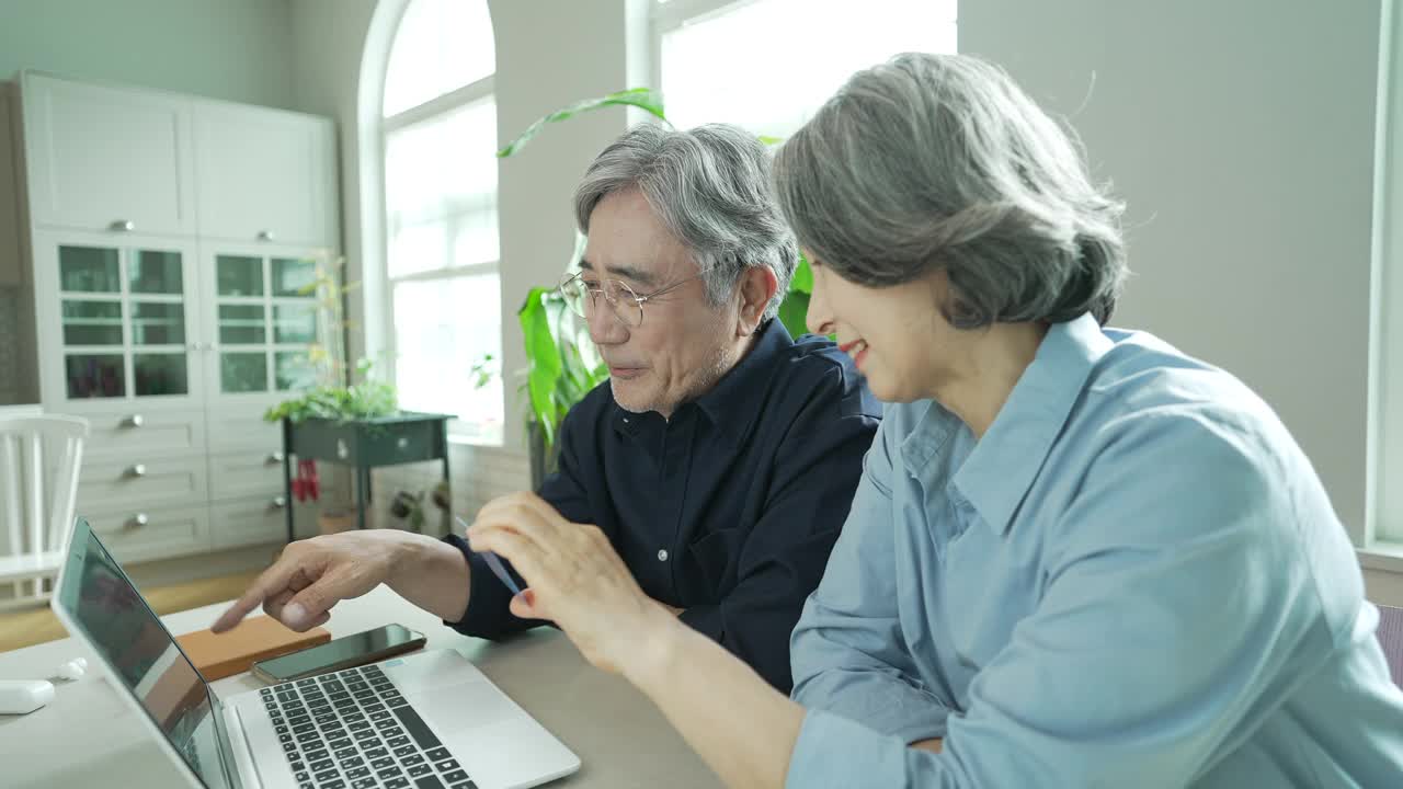 银发冲浪者一代-老男人和女人一边聊天一边看笔记本电脑和信用卡视频素材