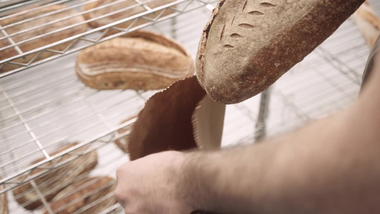 男面包师把新鲜出炉的酸面包装在纸袋里送给面包店的顾客视频素材