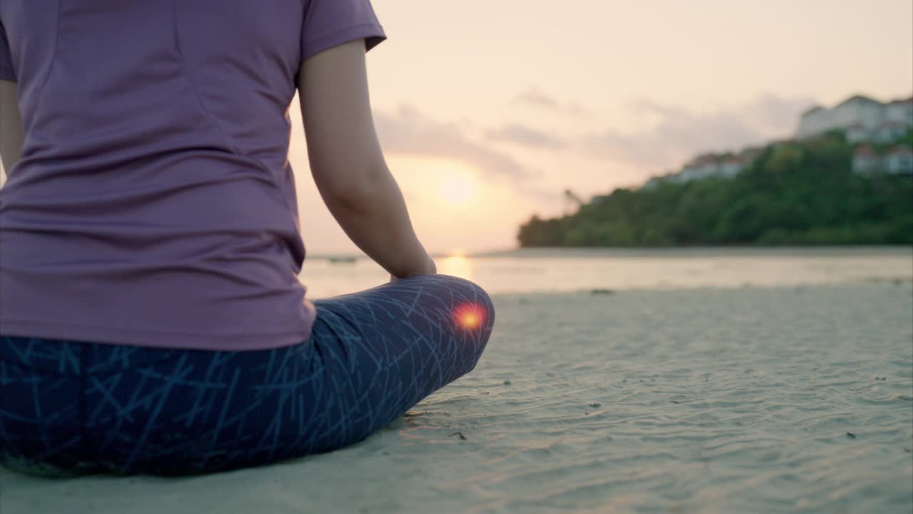 一个美丽的瑜伽女人的剪影坐在莲花的位置上的海滩视频素材