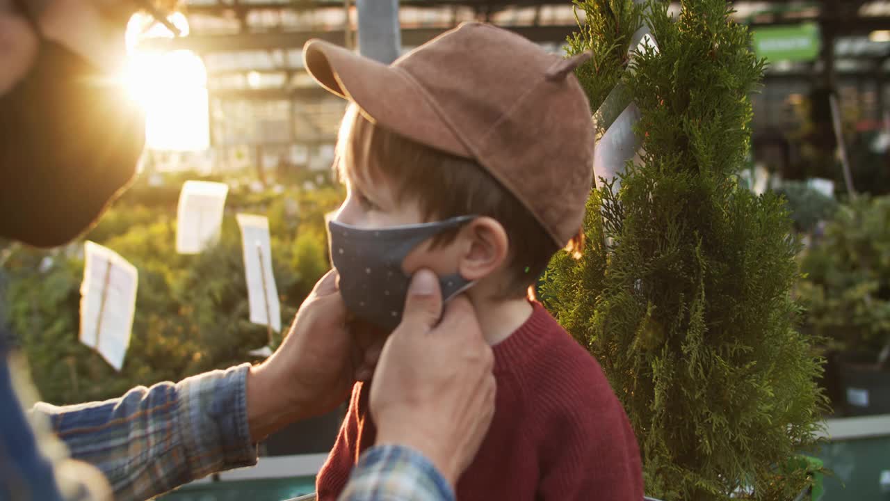 在花园中心购物时，父亲给孩子戴上防护口罩视频素材