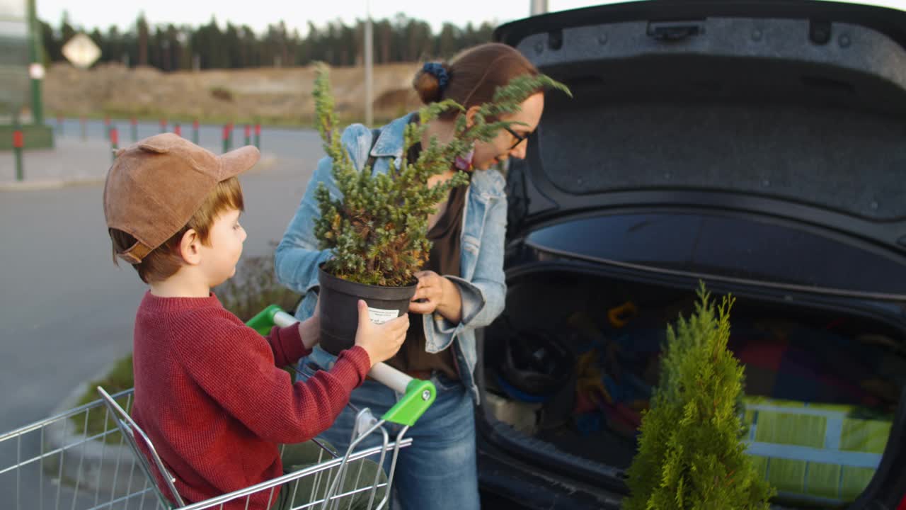 在花园中心购物后，家人在停车场把植物放进车里时戴上防护口罩视频素材