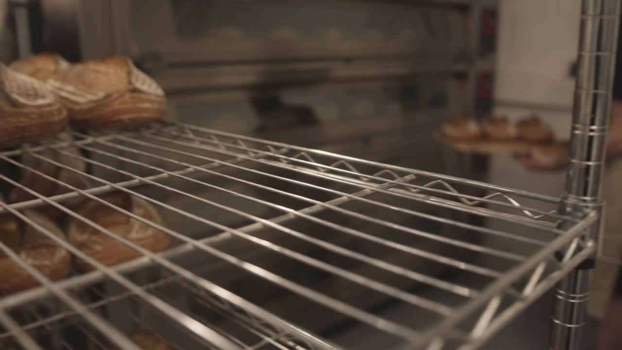 胡子男面包师，在面包房工作，从烤箱中取出新鲜的酸面包视频下载