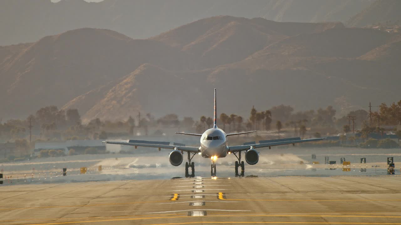 在棕榈树和沙漠山脉的背景下，WS忠诚航空公司的客机在着陆后滚向镜头，然后急转弯离开机场跑道视频素材