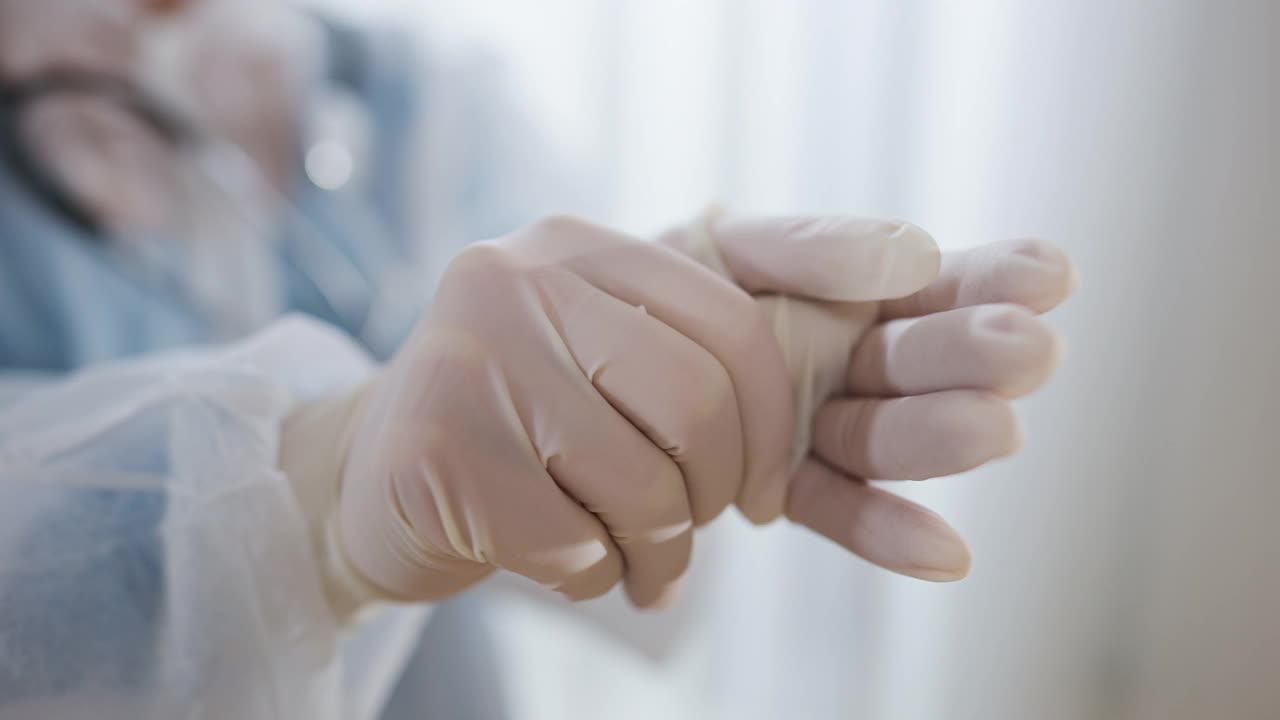 特写女医生的手戴上防护白手套。在医院应对冠状病毒大流行疫情的护士或医生。Covid-19新常态。视频下载