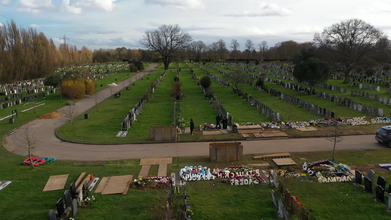 滑动拍摄了一个家庭在墓地的坟墓和一辆汽车，低角度拍摄的空中视频下载