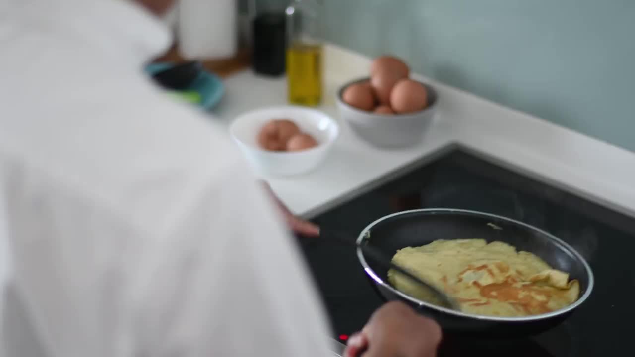 高角度亚洲华人高级男子在厨房用平底锅煎蛋准备早餐视频素材