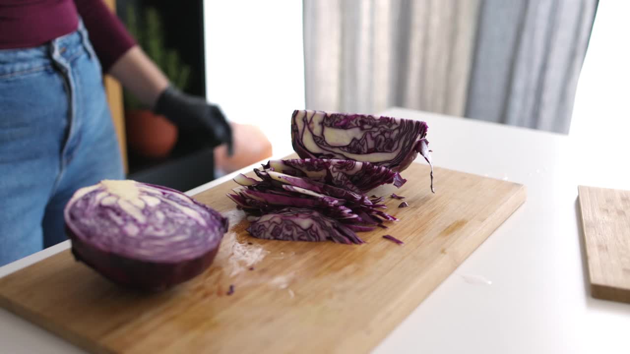 一个匿名的年轻女子在家里的切菜板上切红卷心菜视频素材