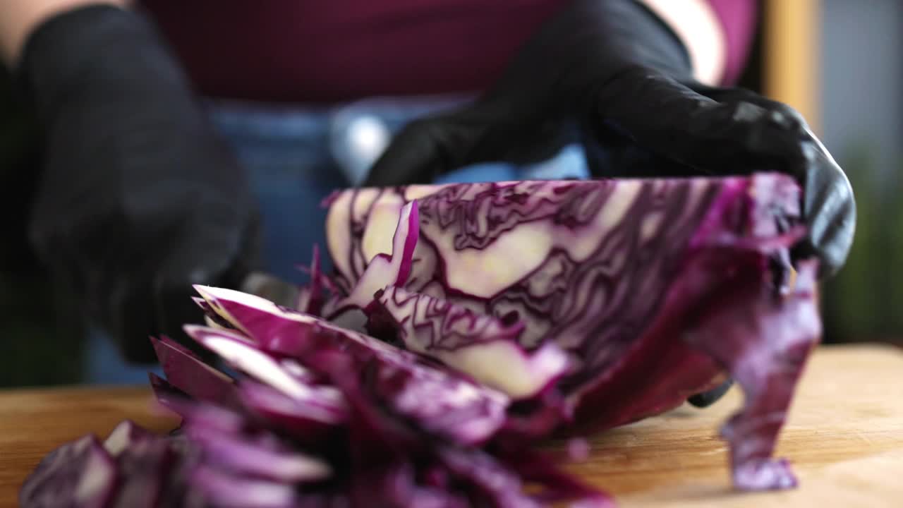 一个匿名的年轻女子在家里的切菜板上切红卷心菜视频素材