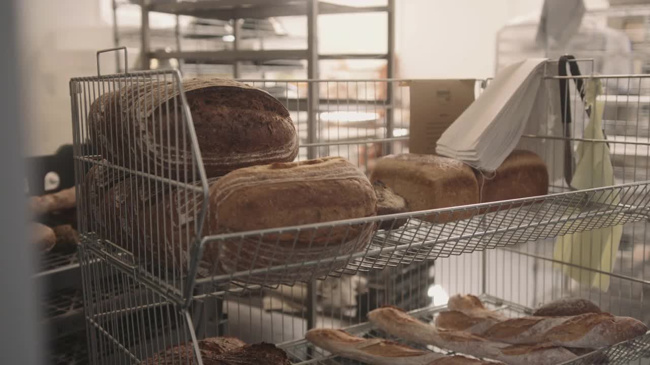 男面包师把新鲜出炉的酸面包装在纸袋里送给面包店的顾客视频下载
