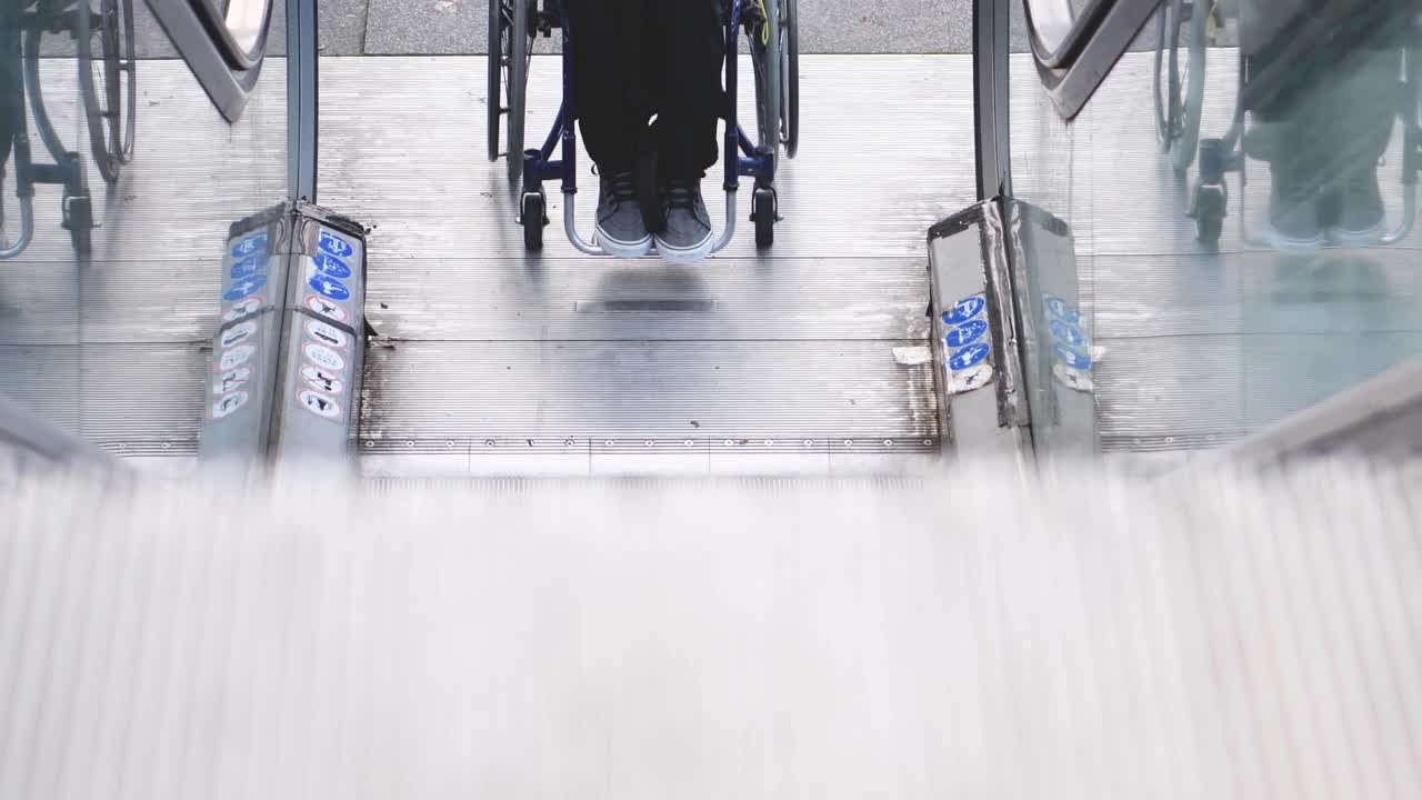 一名残疾人开始用轮椅爬上自动扶梯的视频。视频下载
