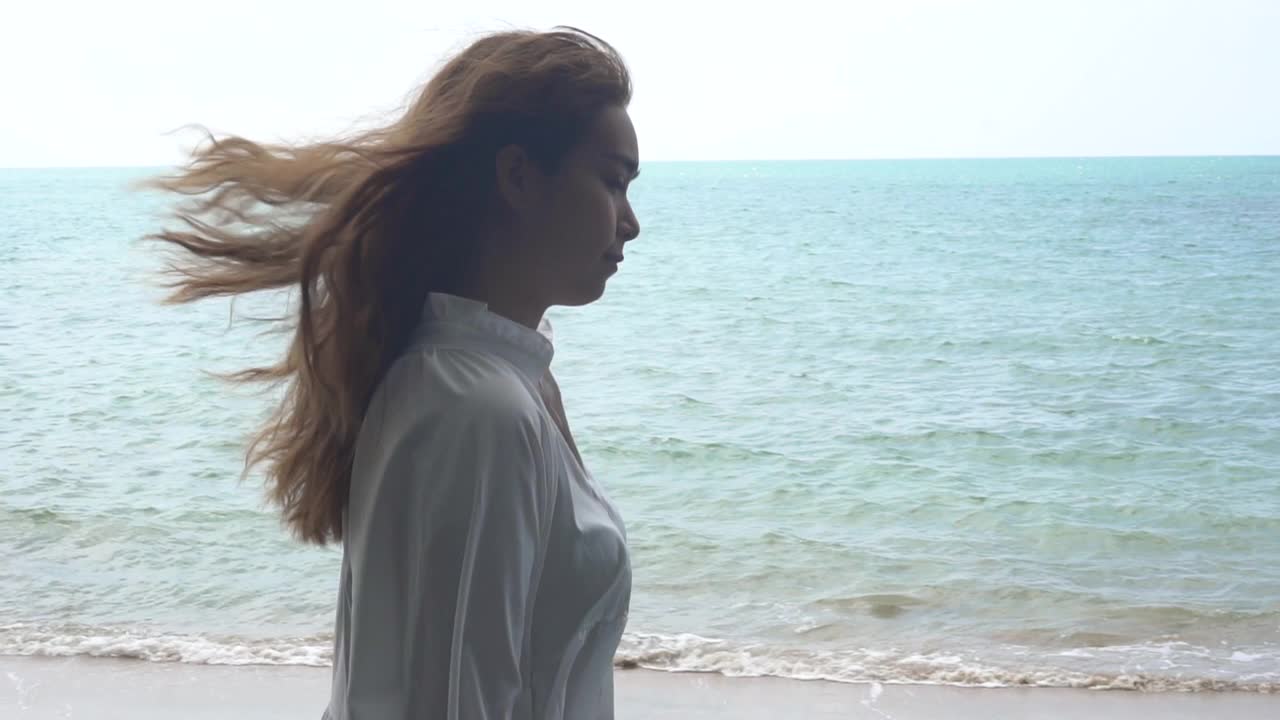 亚洲快乐的年轻女子站在海滩上。视频素材