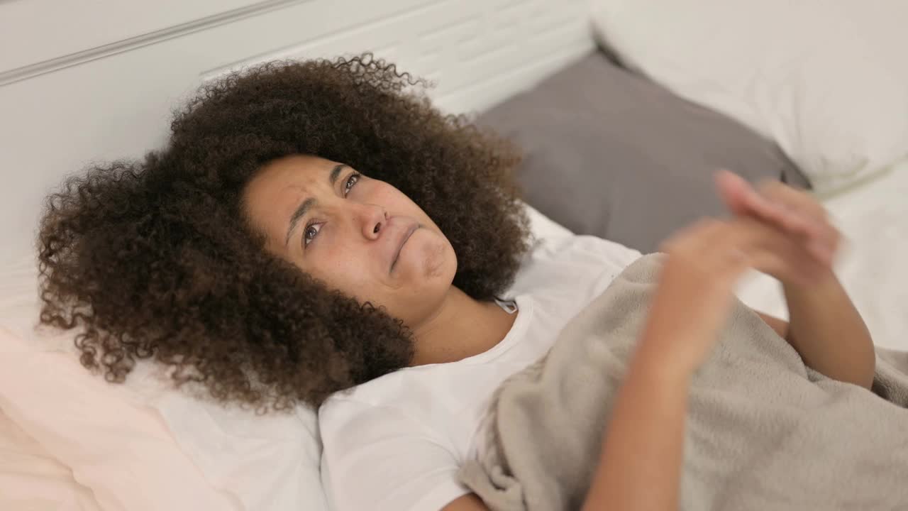 悲伤的年轻非洲妇女躺在床上哭泣视频素材