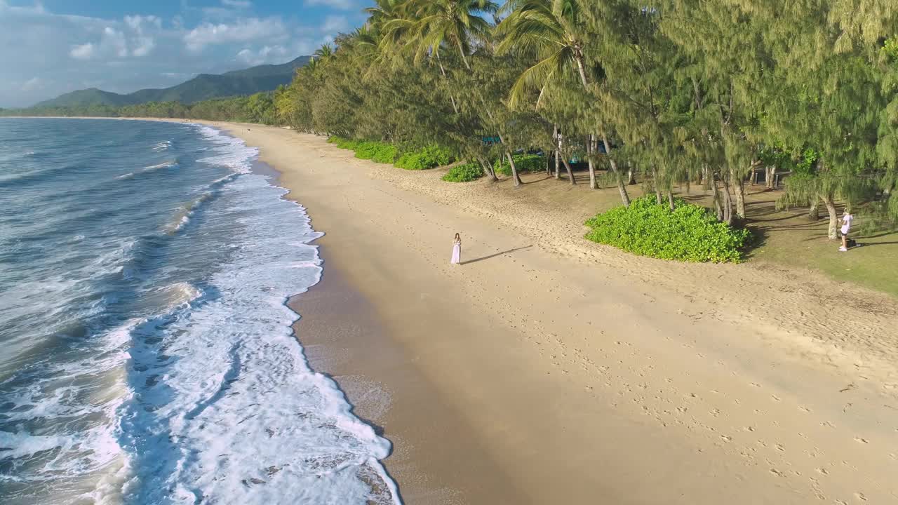 女孩行走在昆士兰凯恩斯热带海滩-无人机4K剪辑视频素材