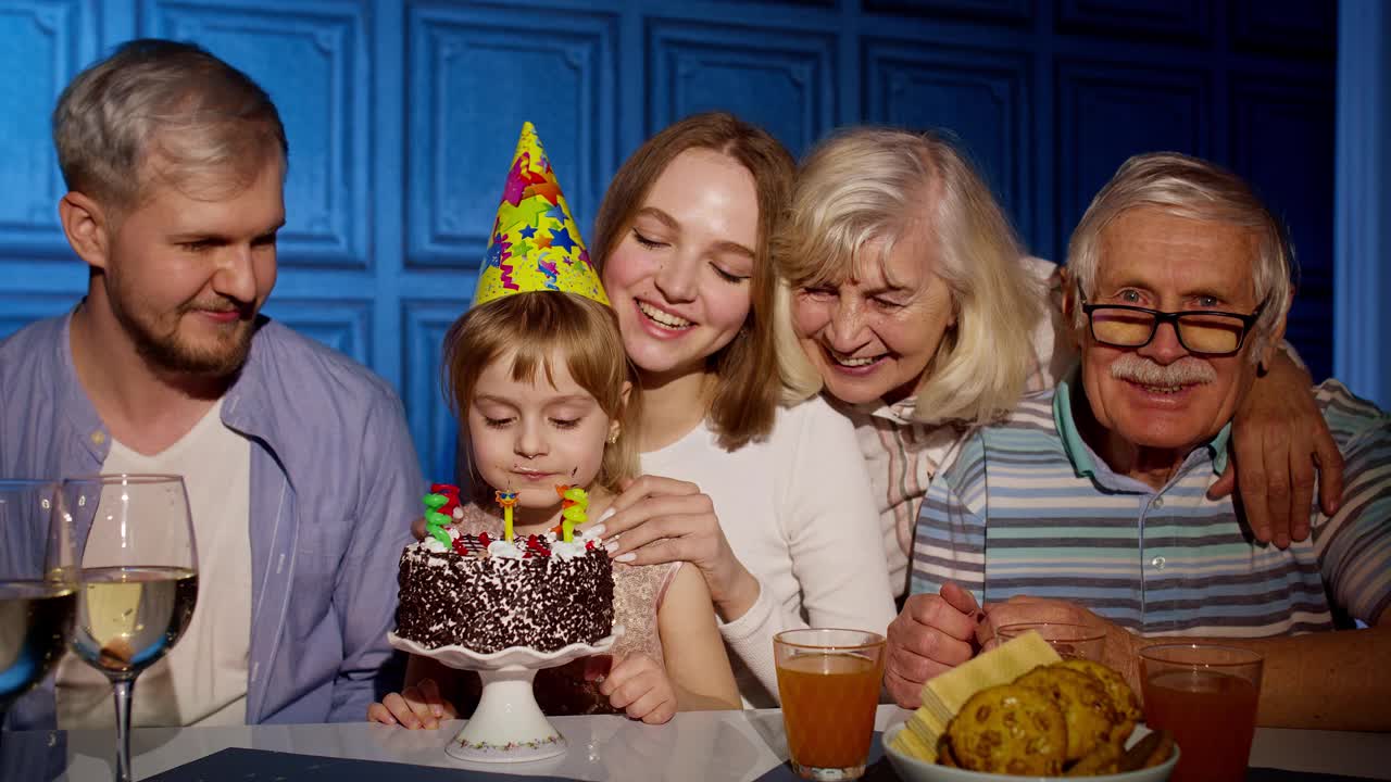 可爱的小女孩吃蛋糕许愿，玩得开心，和家人一起庆祝生日派对视频素材