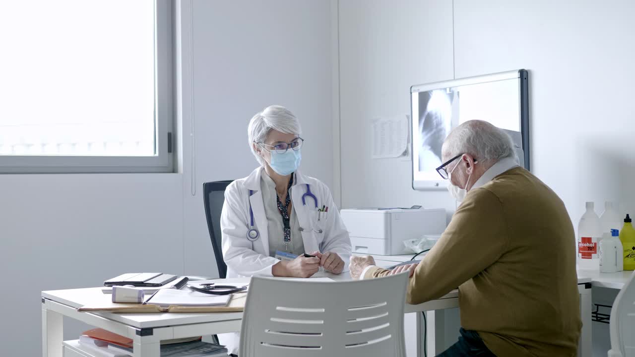 女医生戴着口罩听老病人讲话视频素材
