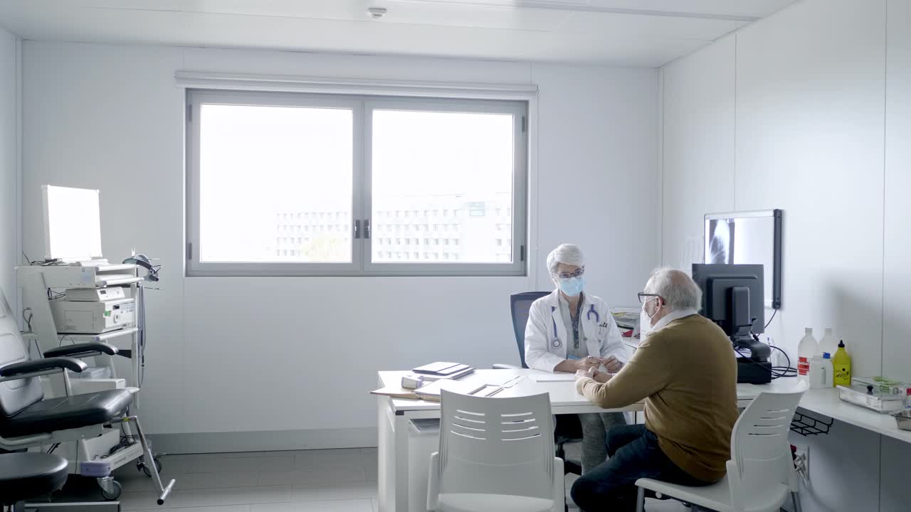 戴防护口罩的医生在门诊咨询老年患者视频素材