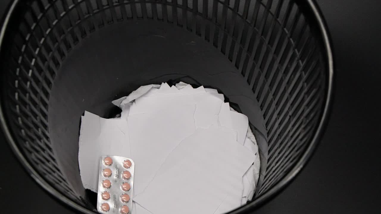 药丸和钞票被扔进废纸篓的慢动作录像视频下载