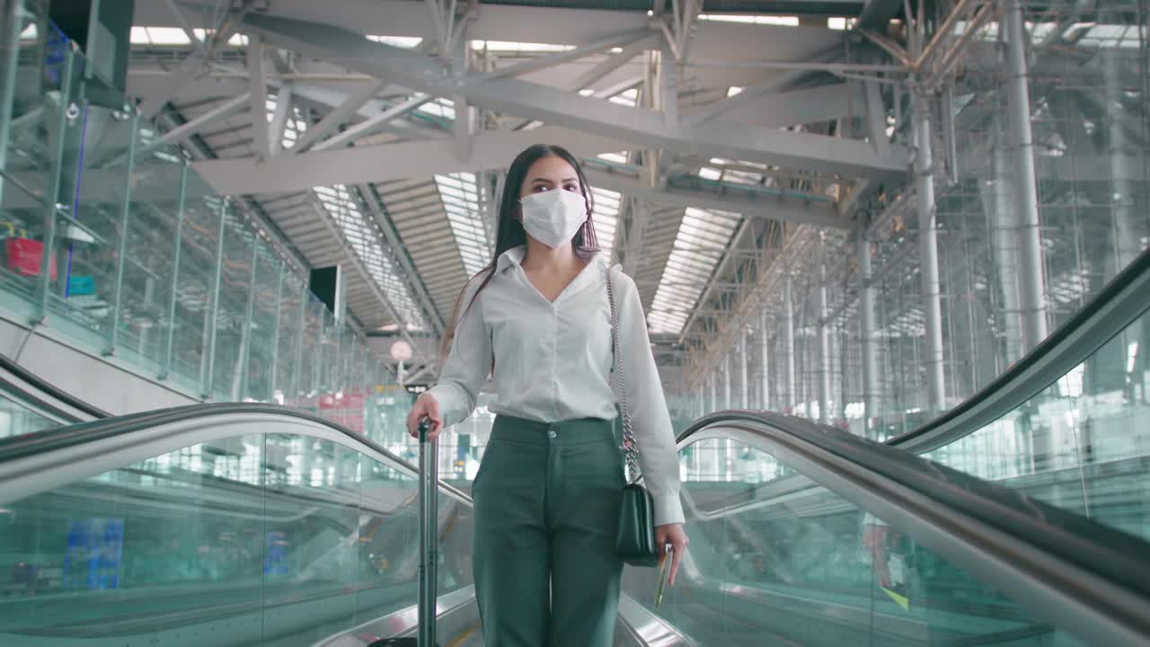 一名商务女性在国际机场戴着防护口罩，在新冠肺炎疫情下旅行，安全旅行，社交距离礼仪，新常态旅行理念视频购买