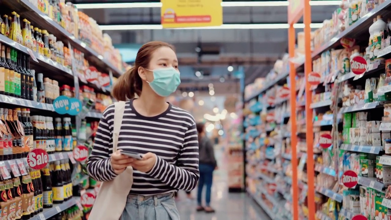 女人在超市购物，戴着口罩。视频素材
