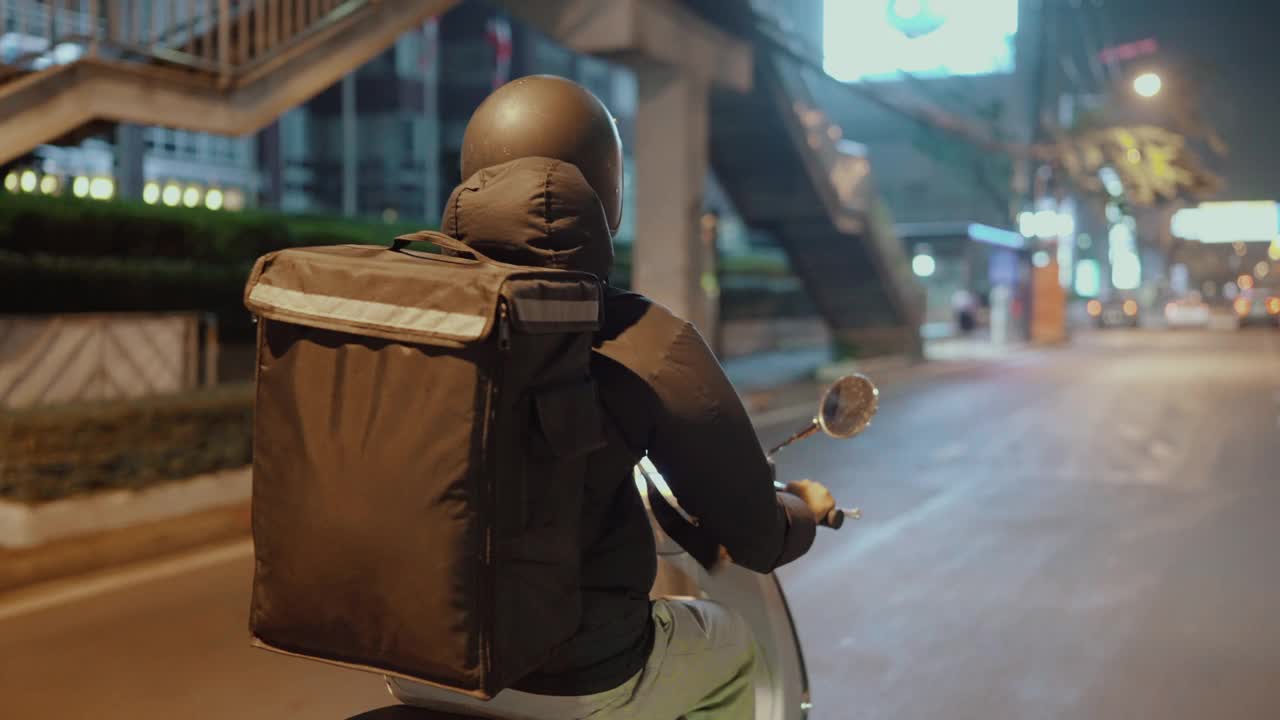 晚上在城市里骑摩托车的快递员视频素材