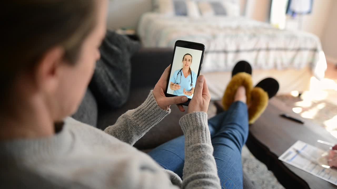 一名女子在家中使用智能手机应用程序咨询医生视频素材
