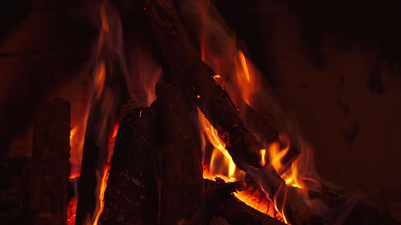 在壁炉里燃烧木头。壁炉里的木柴和火焰。在火焰中冒烟的原木背景。家里舒适的壁炉。特写镜头。视频素材