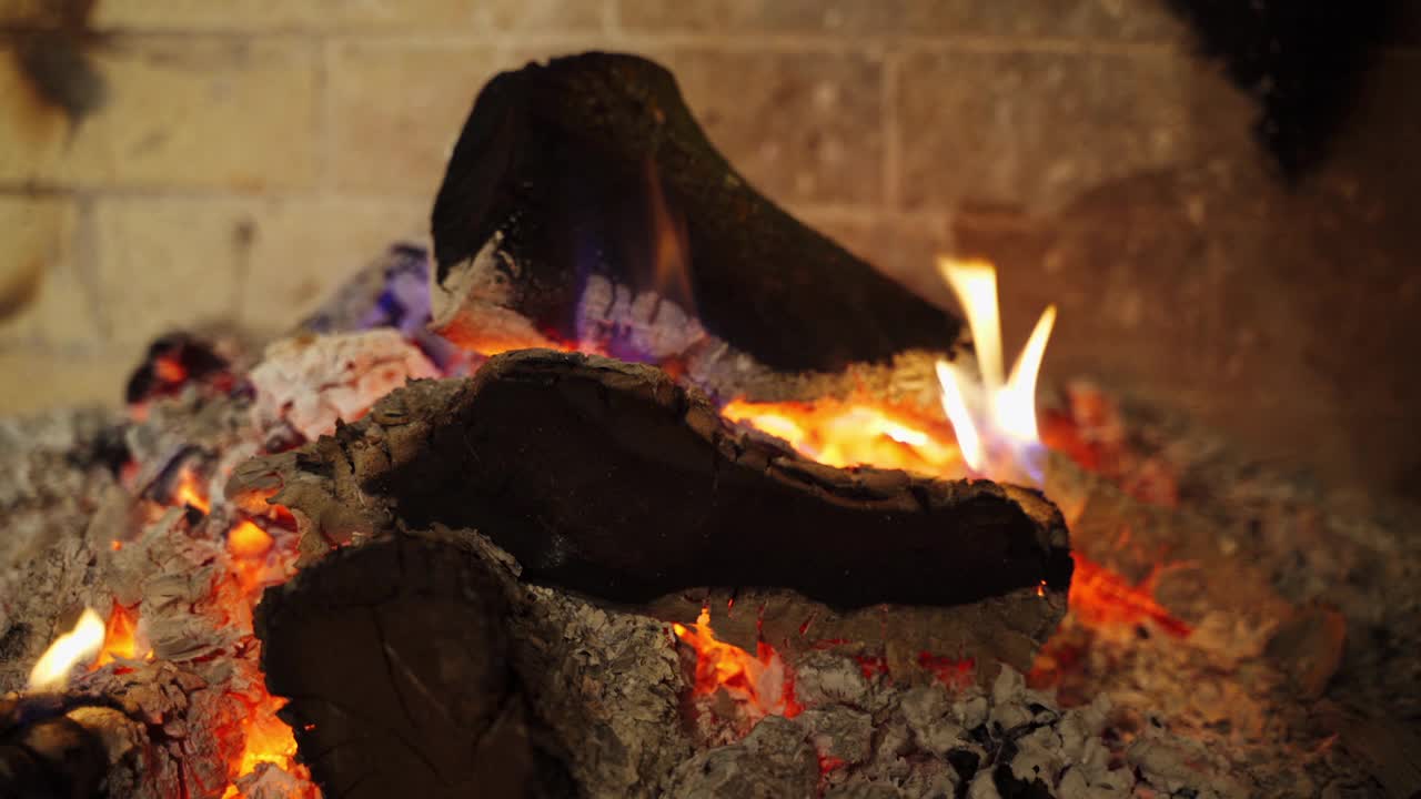 在白灰中闷烧的木头。发光的木头的背景。在壁炉里燃烧的黑木头。舒适温暖的家。视频素材