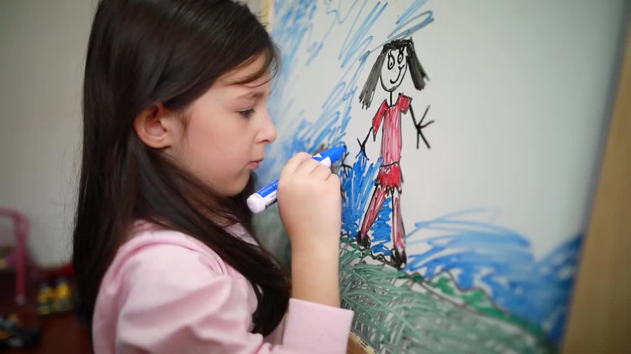 小女孩在玩的时候，用毛笔在家里的白板上画画视频素材