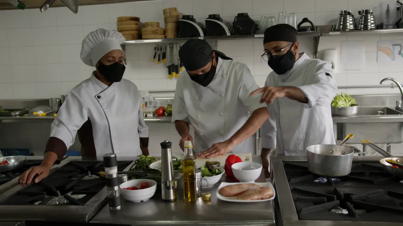 covid-19大流行期间，在餐厅准备食物的厨师团队都戴着防护口罩视频素材