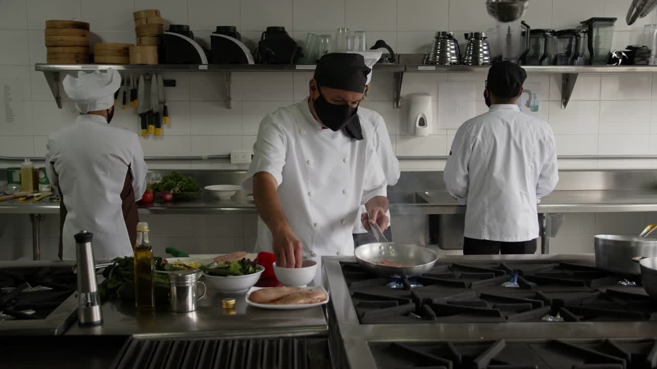厨师、副厨师和烹饪助理在餐厅做饭时都戴着防护口罩视频素材