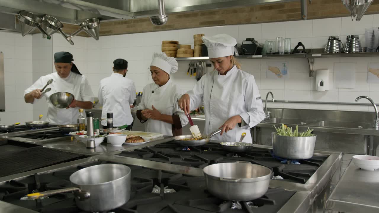 拉丁美洲厨师团队在厨房的餐厅为顾客烹饪和准备饭菜视频素材