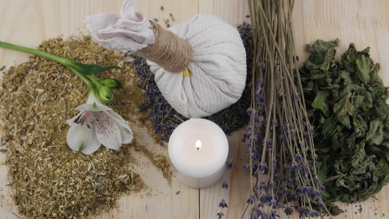 草药袋，干燥的草药，燃烧的蜡烛和白花在木架上视频下载