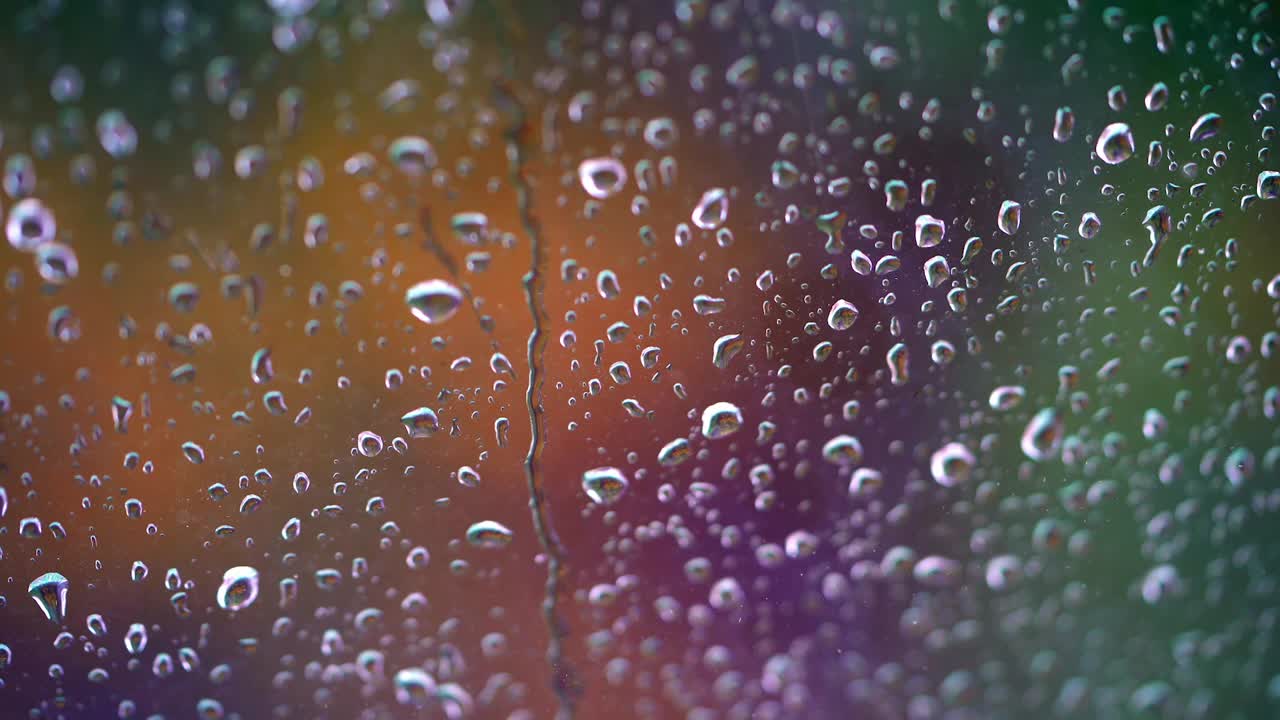 玻璃表面有水滴 多雨的天气 小雨打在窗口 水滴在模糊的彩色背景上顺着窗户流下 特写镜头 视频素材 Id Vcg42n Vcg Com