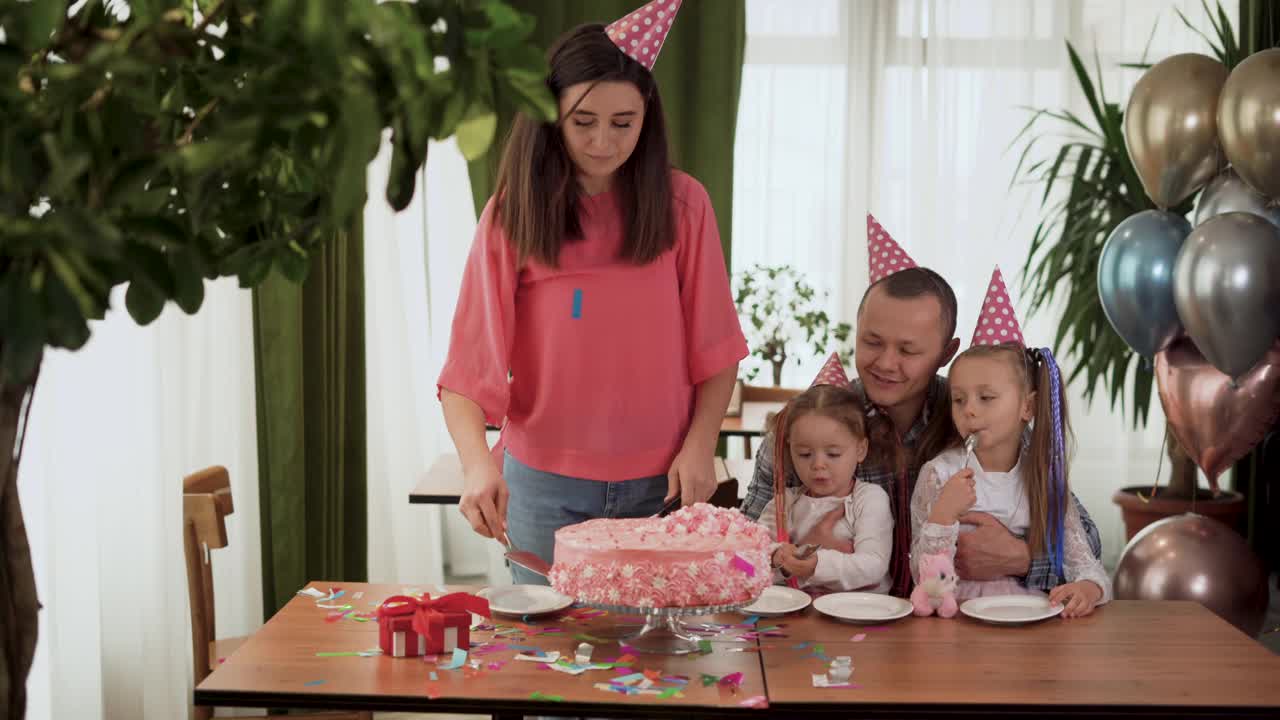 欢乐的家庭聚会。快乐的父母和孩子在室内庆祝他们的生日。妈妈放生日蛋糕。视频素材