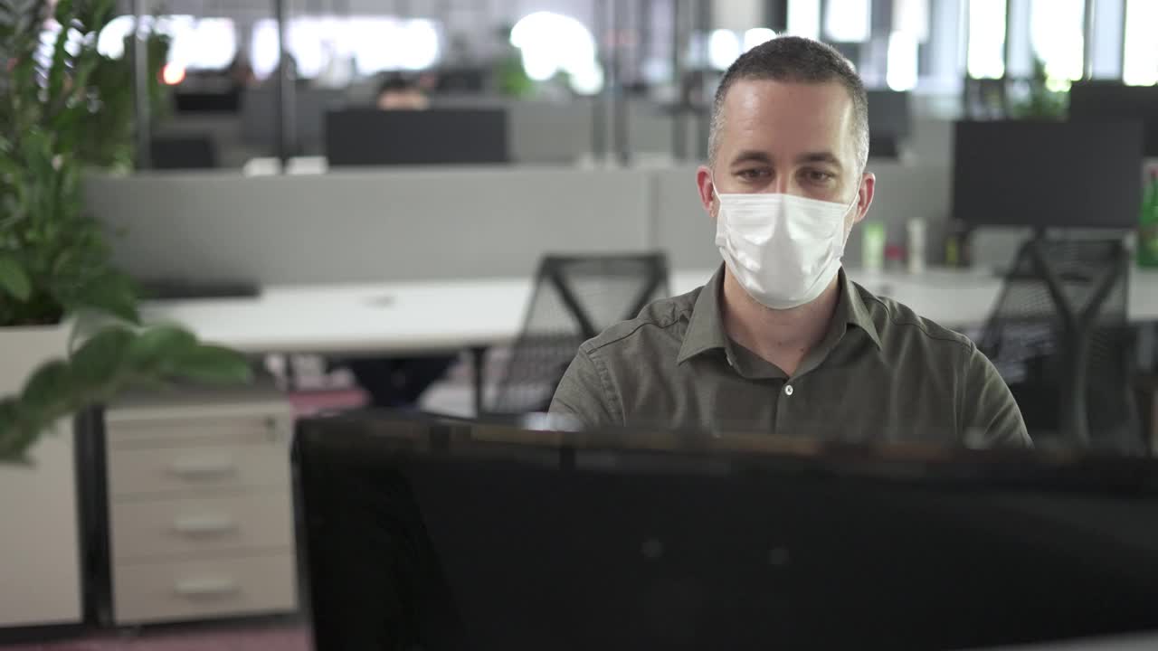 在流感大流行期间戴口罩在办公室工作的商人视频下载