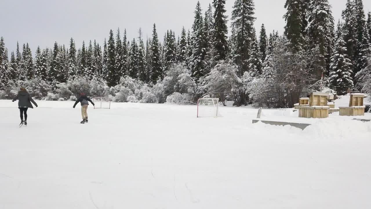 两个孩子在结冰的湖面上溜冰，最后男孩差点摔倒。视频素材