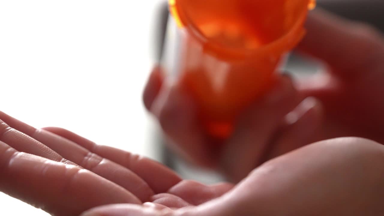 药丸从处方药瓶中倒在手里，动作缓慢视频下载