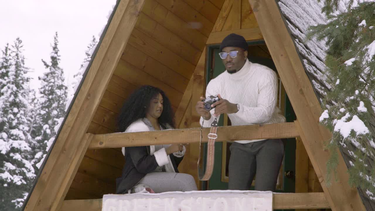 一对夫妇在乡村冬季小屋的阳台上，带着经典的电影摄像机视频下载