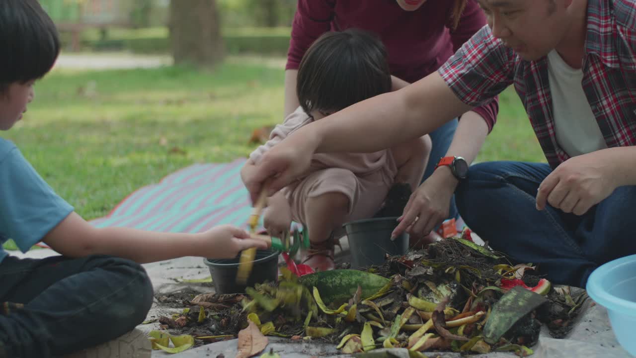 一家人教他们的两个儿子如何用厨房和花园的废弃物制作有机肥料视频素材