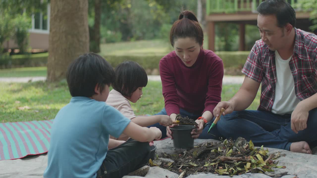 一个家庭教他们的两个儿子如何用厨房和花园的垃圾制造有机肥料视频下载