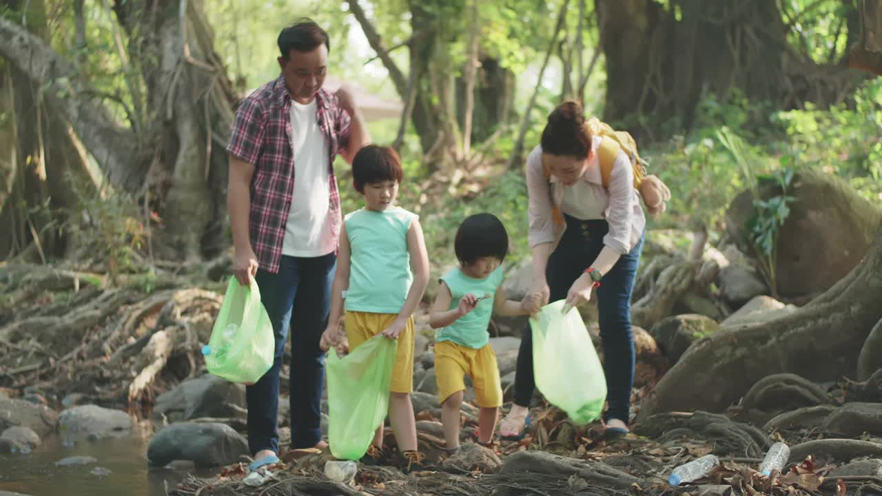 亚洲家庭志愿者在河上捡起一个塑料瓶视频素材