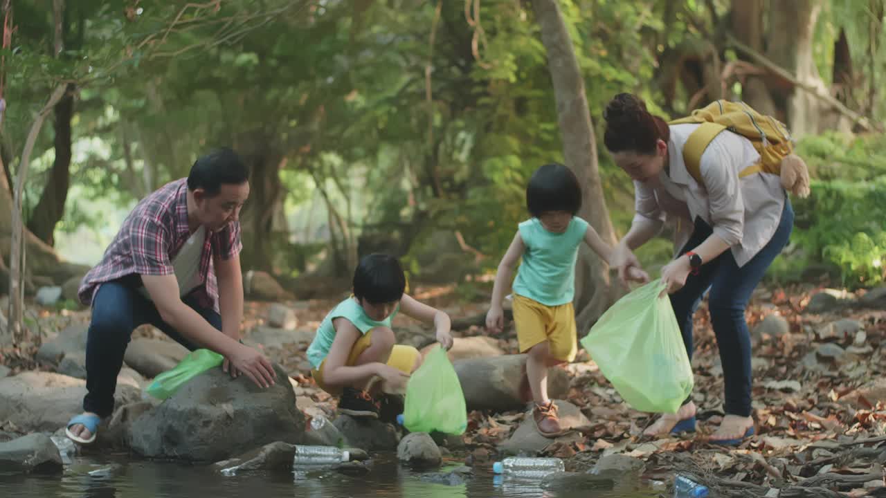 亚洲家庭志愿者在河上捡起一个塑料瓶视频素材