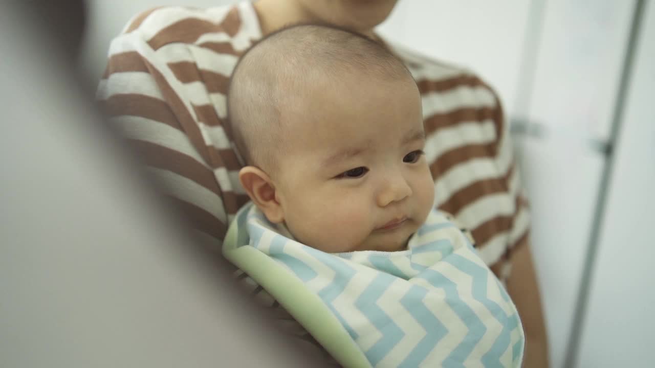 快乐微笑的亚洲母亲和刚出生的小宝贝儿子玩得很开心，在家里的镜子里看着他们的脸。视频素材