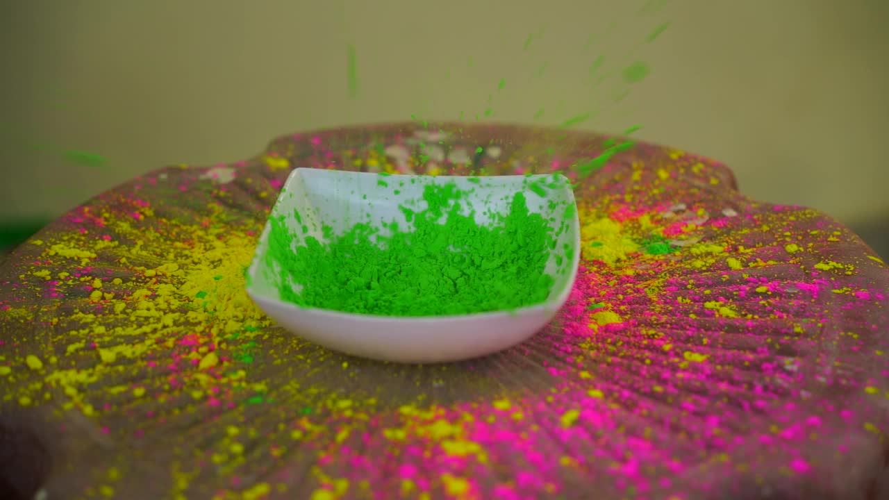胡里节的颜色在白色碗爆炸。彩虹的颜色在空气中飘荡，落在椅子上的碗洞里。胡里节快乐的概念。视频素材