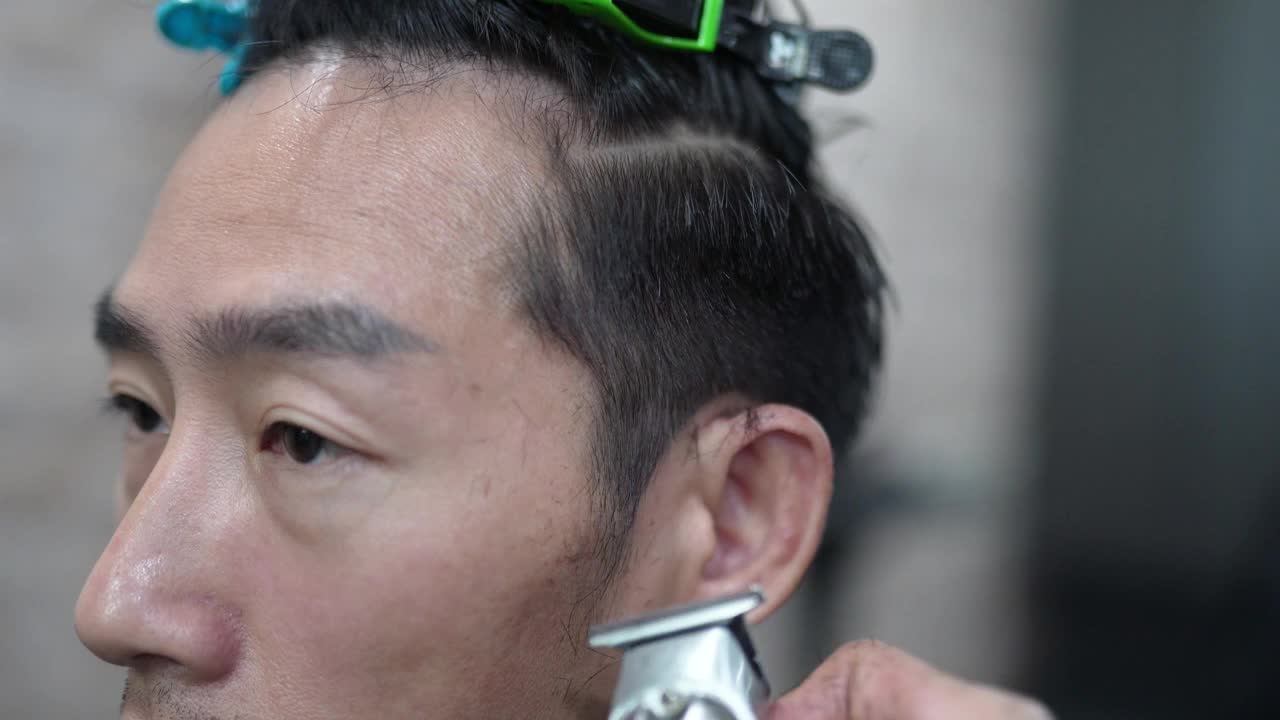 近距离观看，亚洲华人男性理发师在美发厅用理发剪为男士剃毛。理发店。视频素材