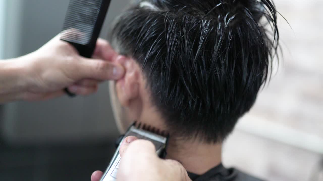 近距离观看，亚洲华人男性理发师在美发厅用理发剪为男士剃毛。理发店。视频下载