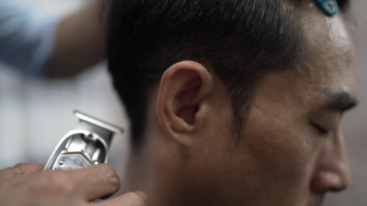 近距离观看，亚洲华人男性美发师在沙龙里用经典的剃须刀剃毛。理发店。视频下载