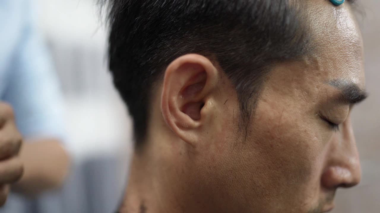 近距离观看，亚洲华人男性美发师在沙龙里用经典的剃须刀剃毛。理发店。视频下载