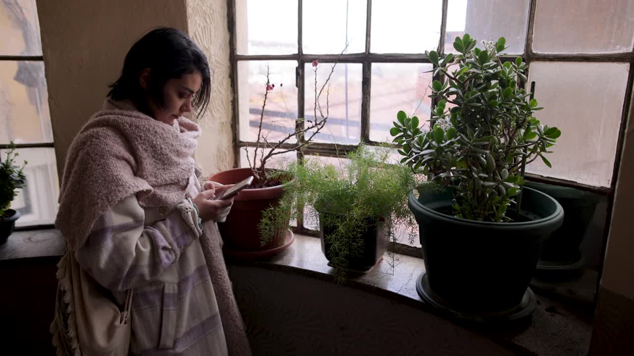 在一幢老建筑的阁楼里，年轻女子拿着手机视频下载